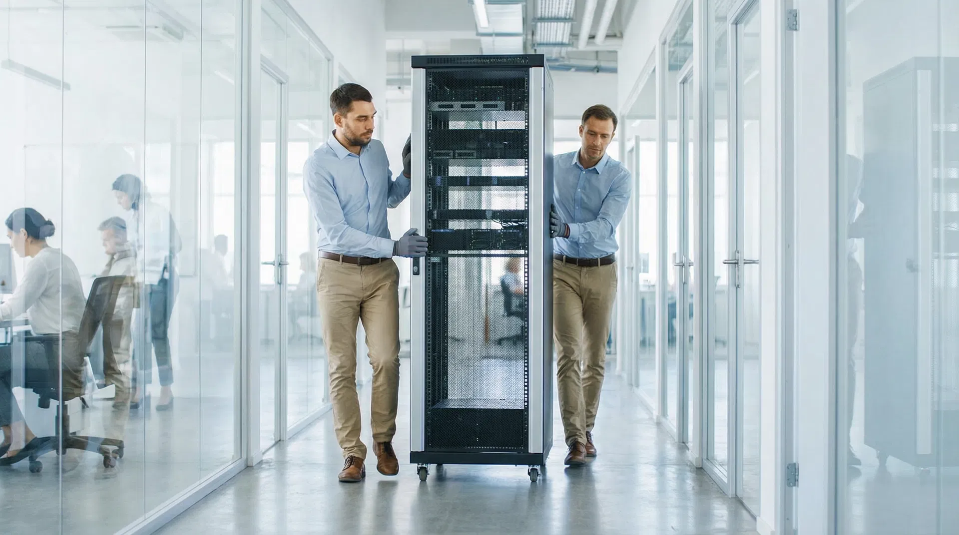 Professional IT team carefully moving server equipment in a modern office hallway